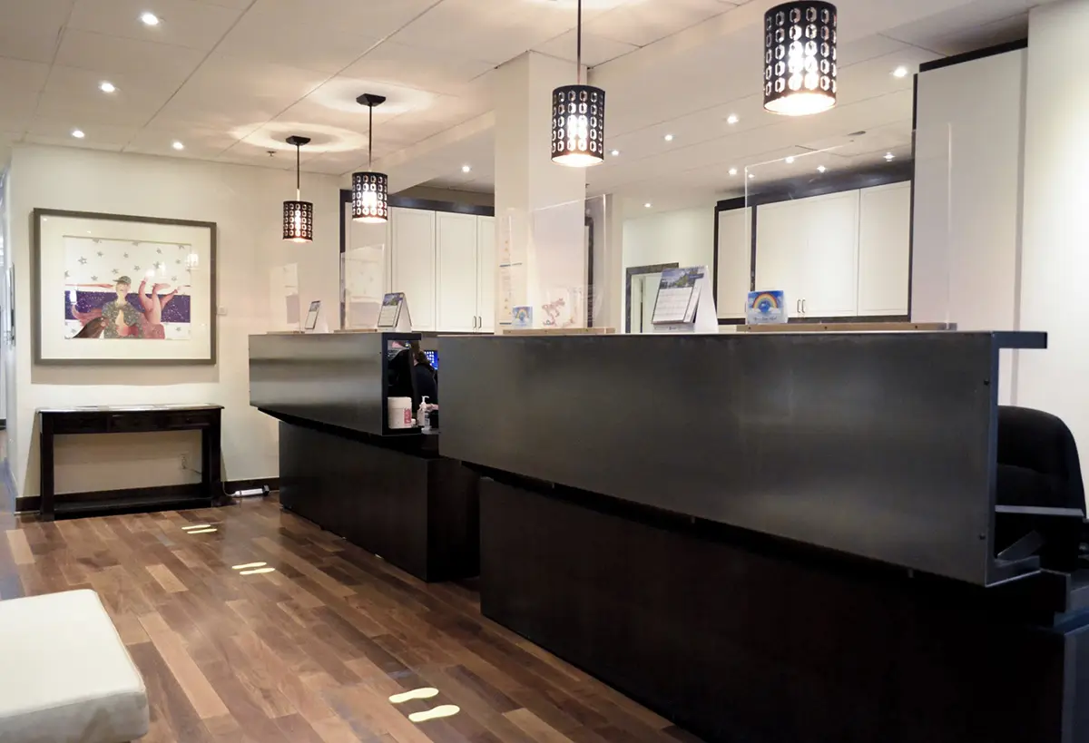 The clinic’s front desk: a dark reception counter under pendant lights, on a wood floor
