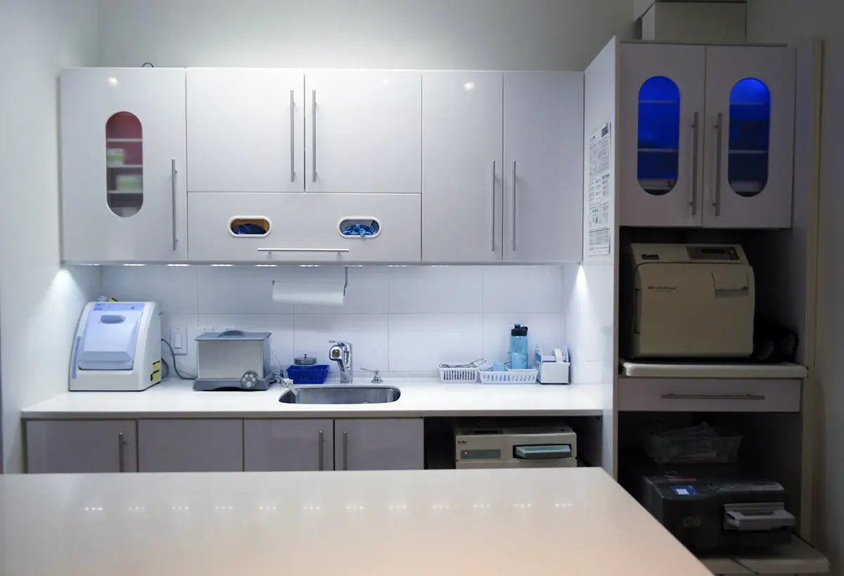 The sterilization room: white cabinets above a counter and sink, and the autoclaves